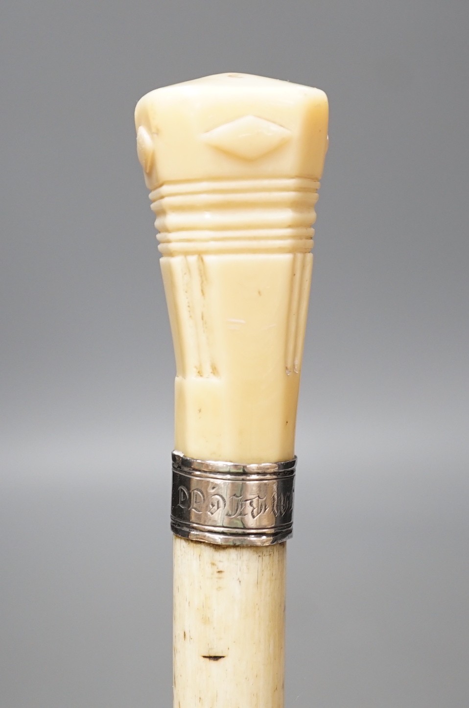 A whale bone walking stick with a whale tooth carved handle, with silver mount, 19th century